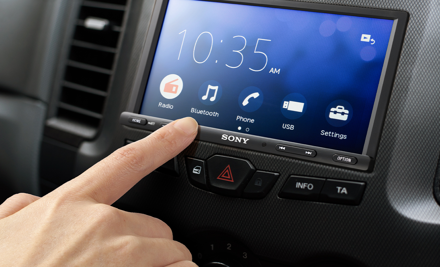 Vista frontal del receptor multimedia digital XAV-1600 con un dedo que toca la pantalla.